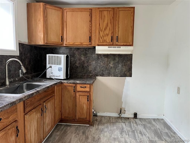 21731 Nevada Ave, Eastpointe, MI 48021 - kitchen featuring under cabinet range hood, brown cabinetry, tasteful backsplash, and dark countertops