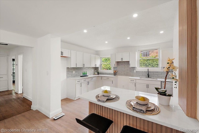 17155 Wisconsin St, Detroit, MI 48221 - kitchen featuring a sink, a peninsula, tasteful backsplash, white cabinetry, and recessed lighting