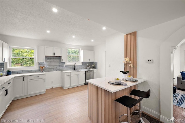 17155 Wisconsin St, Detroit, MI 48221 - kitchen with a sink, stainless steel dishwasher, light wood-style floors, a kitchen bar, and decorative backsplash