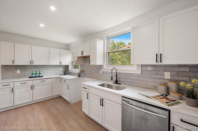 17155 Wisconsin St, Detroit, MI 48221 - kitchen featuring stainless steel dishwasher, a sink, white cabinets, backsplash, and light wood-style flooring