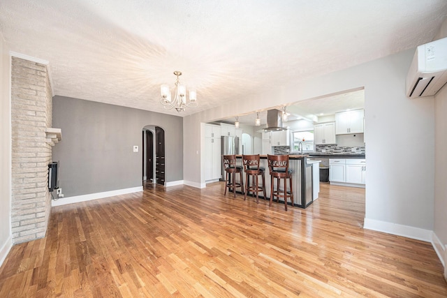 455 N 10th St, Plainwell, MI 49080 - living area featuring arched walkways, light wood finished floors, a wall mounted AC, and baseboards