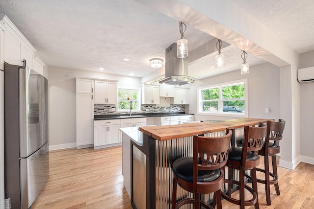 455 N 10th St, Plainwell, MI 49080 - kitchen featuring freestanding refrigerator, a textured ceiling, baseboards, butcher block countertops, and a sink