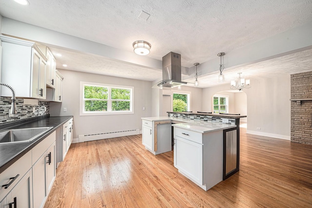 455 N 10th St, Plainwell, MI 49080 - kitchen with baseboard heating, a sink, island exhaust hood, arched walkways, and a center island