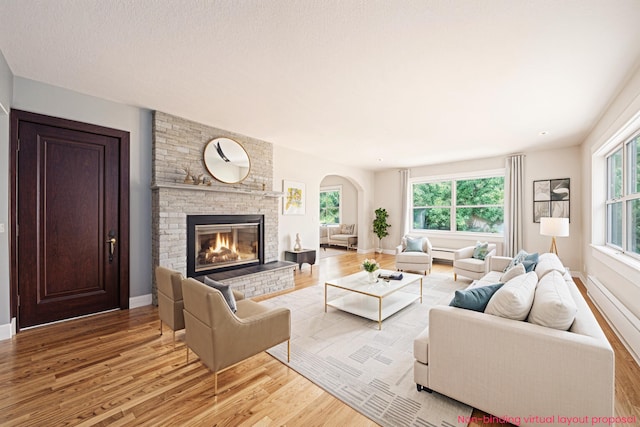 455 N 10th St, Plainwell, MI 49080 - living room featuring light wood finished floors, healthy amount of natural light, a brick fireplace, and arched walkways