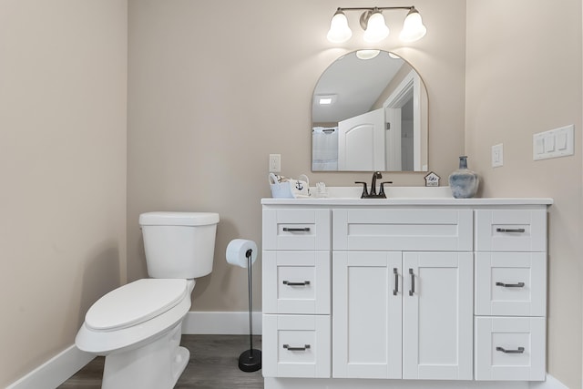 3551 W W Lake Mitchell Dr, Cadillac, MI 49601 - bathroom with baseboards, toilet, vanity, and wood finished floors