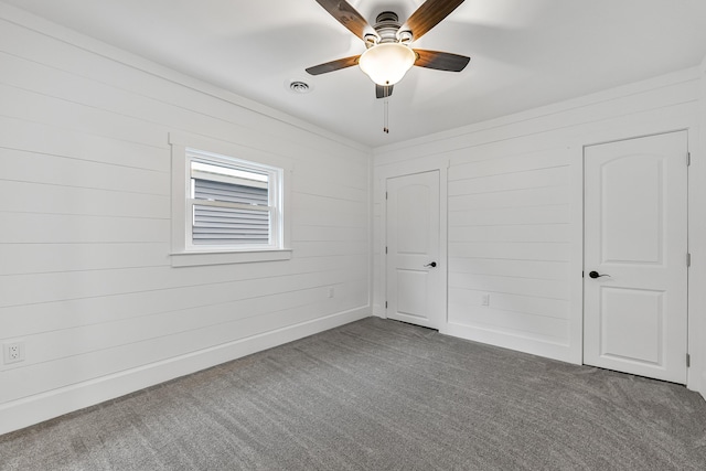3551 W W Lake Mitchell Dr, Cadillac, MI 49601 - unfurnished bedroom with carpet floors, wooden walls, and ceiling fan
