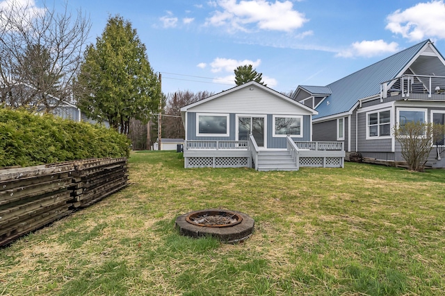 3551 W W Lake Mitchell Dr, Cadillac, MI 49601 - back of house featuring a fire pit, a deck, a lawn, and metal roof