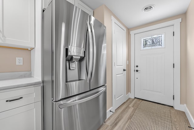3551 W W Lake Mitchell Dr, Cadillac, MI 49601 - kitchen with stainless steel fridge with ice dispenser, white cabinetry, light wood-style flooring, and baseboards