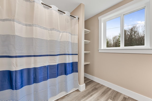 3551 W W Lake Mitchell Dr, Cadillac, MI 49601 - bathroom featuring wood finished floors, baseboards, and a shower with shower curtain