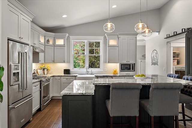2582 3 Mile Rd NE, Grand Rapids, MI 49525 - kitchen featuring premium appliances, a sink, under cabinet range hood, a kitchen bar, and backsplash