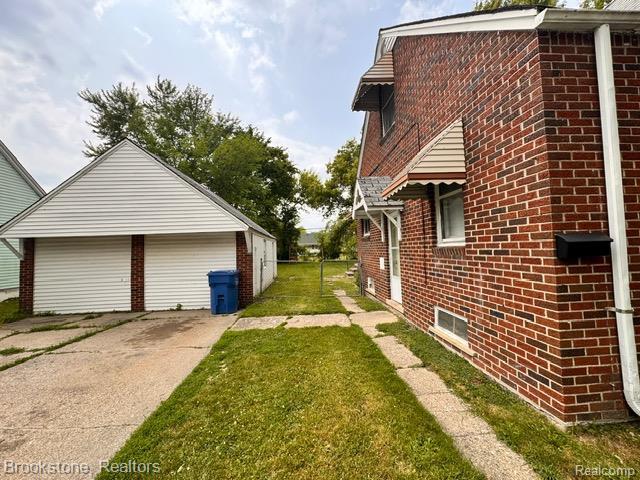 20951 Nummer St, Warren, MI 48089 - view of property exterior with brick siding, a detached garage, and a lawn