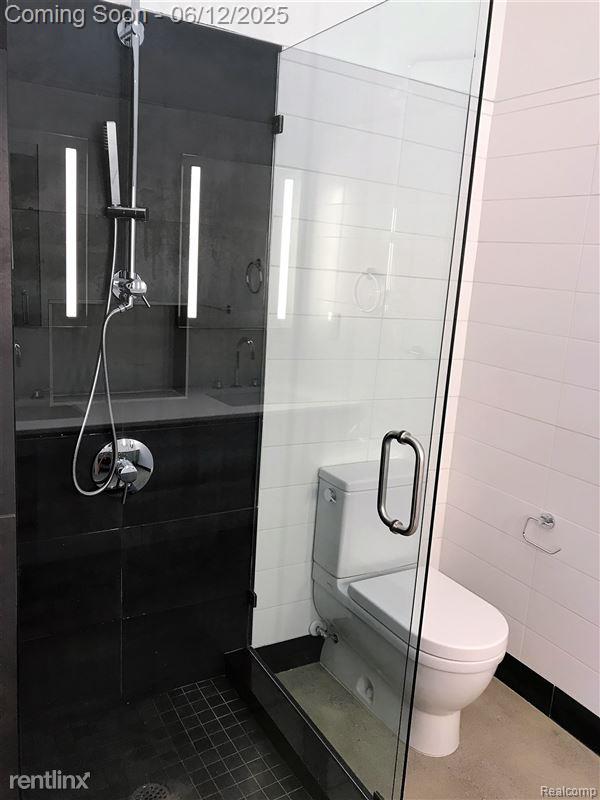 1454 Townsend St Unit 101, Detroit, MI 48214 - full bath featuring toilet, a stall shower, a sink, and tile walls