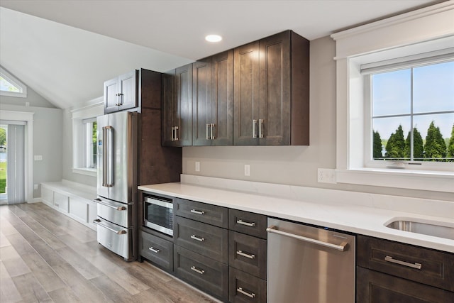 5150 Redding Dr, Pinckney, MI 48169 - kitchen with stainless steel appliances, dark brown cabinets, light wood-style floors, vaulted ceiling, and recessed lighting
