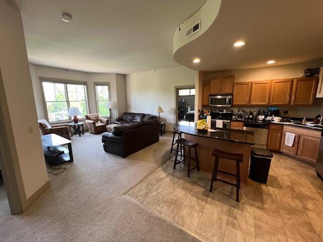 600 Albert Ave Unit 524, East Lansing, MI 48823 - kitchen with stainless steel appliances, dark countertops, a kitchen breakfast bar, brown cabinetry, and recessed lighting