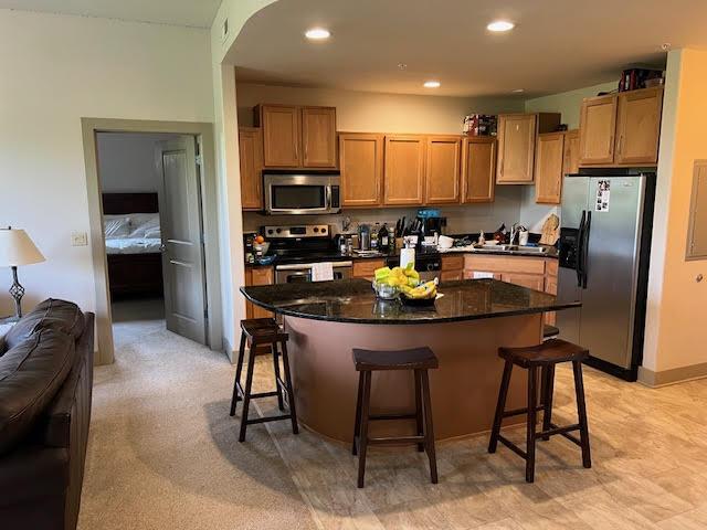 600 Albert Ave Unit 524, East Lansing, MI 48823 - kitchen featuring appliances with stainless steel finishes, a kitchen breakfast bar, open floor plan, a kitchen island, and a sink