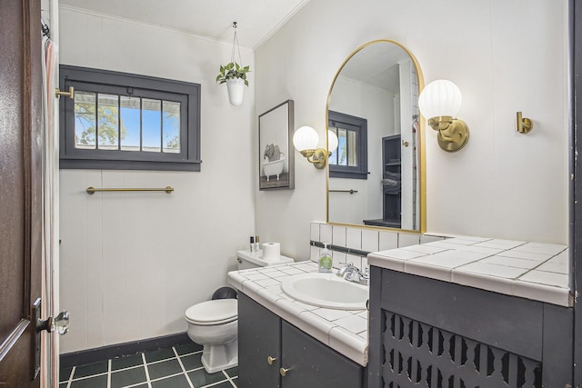 2046 Bourdon St, Muskegon, MI 49441 - full bathroom with vanity, toilet, crown molding, tile patterned flooring, and baseboards