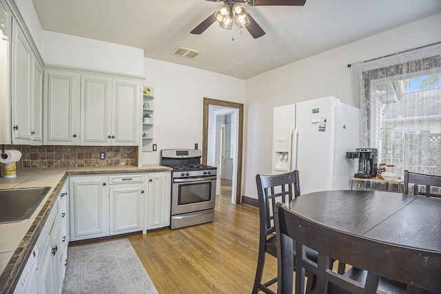 2046 Bourdon St, Muskegon, MI 49441 - kitchen featuring gas range, white refrigerator with ice dispenser, ceiling fan, light wood finished floors, and open shelves