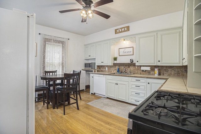 2046 Bourdon St, Muskegon, MI 49441 - kitchen with gas range oven, open shelves, white dishwasher, ceiling fan, and backsplash