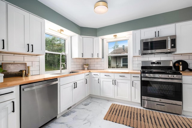 1700 Bristol Ave NW, Grand Rapids, MI 49504 - kitchen featuring butcher block counters, stainless steel appliances, a sink, light marble finish flooring, and tasteful backsplash