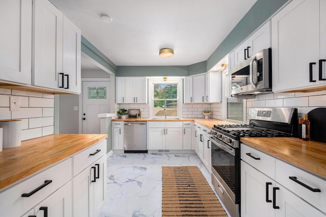 1700 Bristol Ave NW, Grand Rapids, MI 49504 - kitchen featuring wooden counters, appliances with stainless steel finishes, light marble finish flooring, tasteful backsplash, and a sink