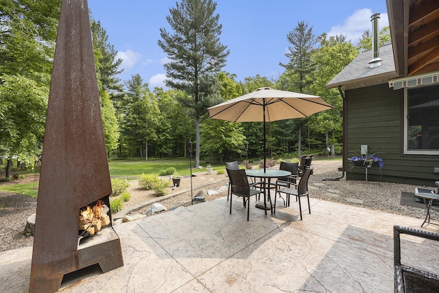 6838 E Michillinda Rd, Twin Lake, MI 49457 - view of patio with a lit fireplace, outdoor dining area, and view of wooded area