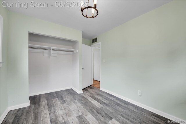 6927 Snow Apple Dr, Clarkston, MI 48346 - unfurnished bedroom featuring a chandelier, wood finished floors, a closet, and baseboards