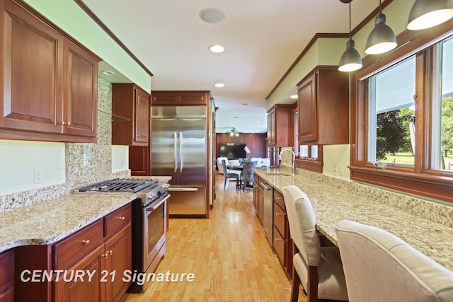 12 W Corral Dr, Saginaw, MI 48638 - kitchen with high end appliances, a sink, light wood-style flooring, light stone countertops, and recessed lighting