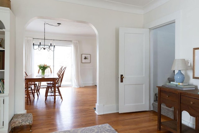 1550 Pine Ave NW, Grand Rapids, MI 49504 - dining space featuring arched walkways, a chandelier, wood finished floors, crown molding, and baseboards