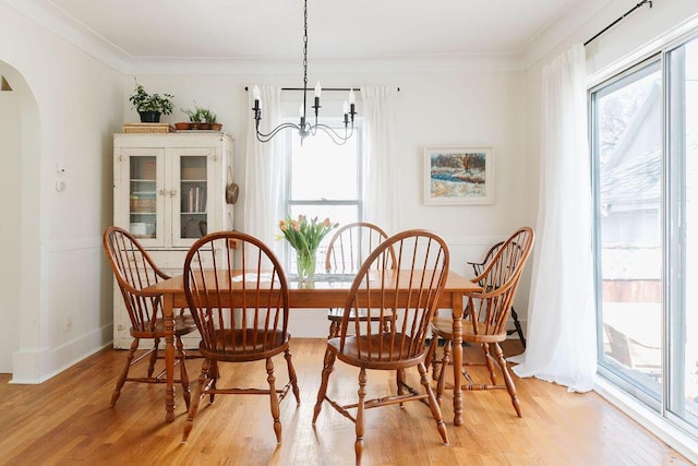 1550 Pine Ave NW, Grand Rapids, MI 49504 - dining area featuring arched walkways, light wood-style flooring, a chandelier, crown molding, and baseboards