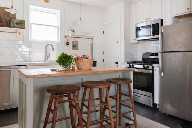 1550 Pine Ave NW, Grand Rapids, MI 49504 - kitchen with stainless steel appliances, a sink, white cabinetry, light countertops, and a breakfast bar