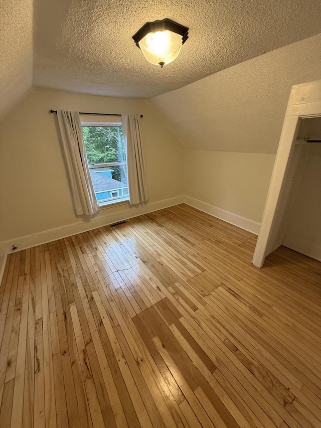 106 S Berkley St, Kalamazoo, MI 49006 - additional living space featuring light wood-style floors, a textured ceiling, baseboards, and vaulted ceiling