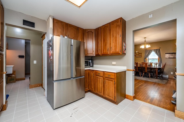 2311 E Glendora Rd, Buchanan, MI 49107 - kitchen featuring freestanding refrigerator, brown cabinets, light countertops, and a chandelier