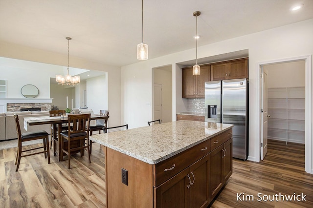 12285 Apple Cart Ln, Lowell, MI 49331 - kitchen featuring stainless steel fridge, light wood-style floors, tasteful backsplash, a center island, and light stone countertops