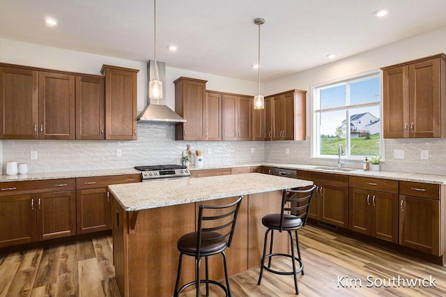 12285 Apple Cart Ln, Lowell, MI 49331 - kitchen featuring wall chimney range hood, a sink, wood finished floors, a kitchen island, and a breakfast bar area