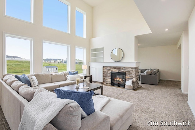 12285 Apple Cart Ln, Lowell, MI 49331 - carpeted living room featuring plenty of natural light, built in shelves, a towering ceiling, baseboards, and a stone fireplace