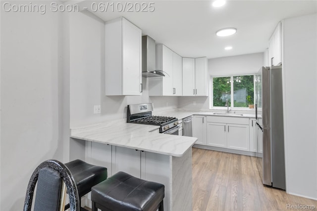 2062 Vermont Dr, Troy, MI 48083 - kitchen featuring appliances with stainless steel finishes, a sink, wall chimney range hood, a peninsula, and light stone countertops