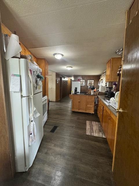 583 S Mcintosh Ln, Muskegon, MI 49442 - kitchen with a peninsula, white appliances, brown cabinetry, dark countertops, and dark wood-style floors