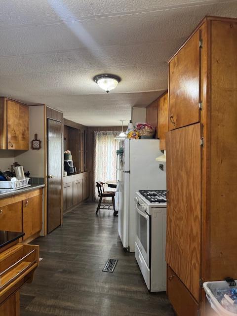 583 S Mcintosh Ln, Muskegon, MI 49442 - kitchen with white range with gas stovetop, brown cabinetry, dark wood finished floors, and a textured ceiling
