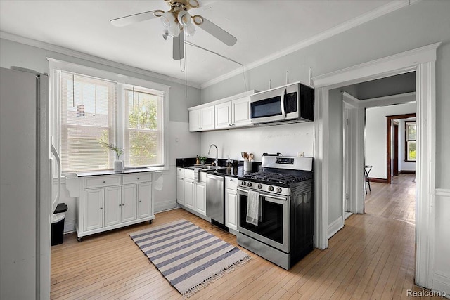 2160 Concord St, Detroit, MI 48207 - kitchen with appliances with stainless steel finishes, ceiling fan, light wood-style floors, ornamental molding, and white cabinets