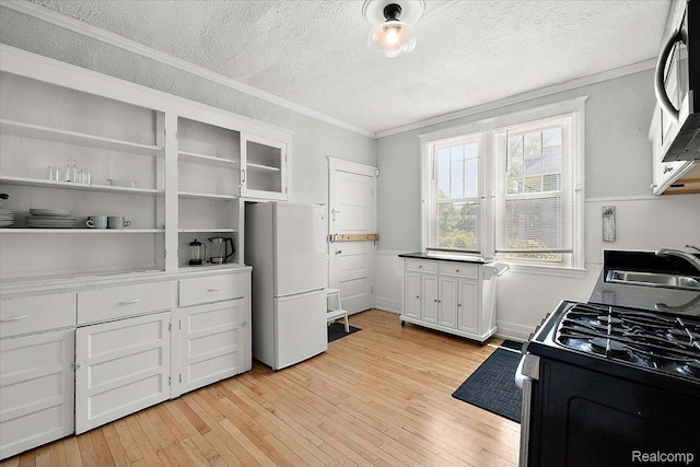2160 Concord St, Detroit, MI 48207 - kitchen with freestanding refrigerator, range with gas cooktop, stainless steel microwave, ornamental molding, and a textured ceiling