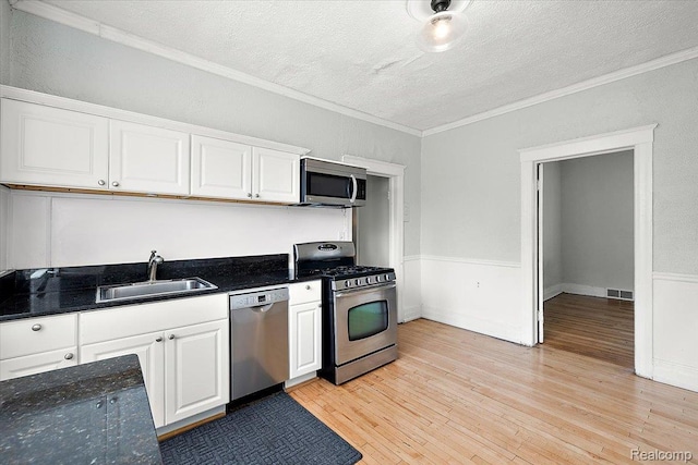 2160 Concord St, Detroit, MI 48207 - kitchen featuring appliances with stainless steel finishes, a textured ceiling, crown molding, white cabinets, and light wood-style floors