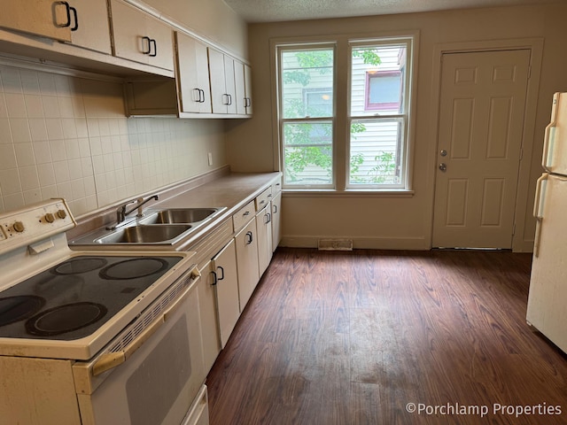 1257 3rd St, Muskegon, MI 49441 - kitchen with white appliances, a sink, white cabinets, light countertops, and dark wood-style flooring