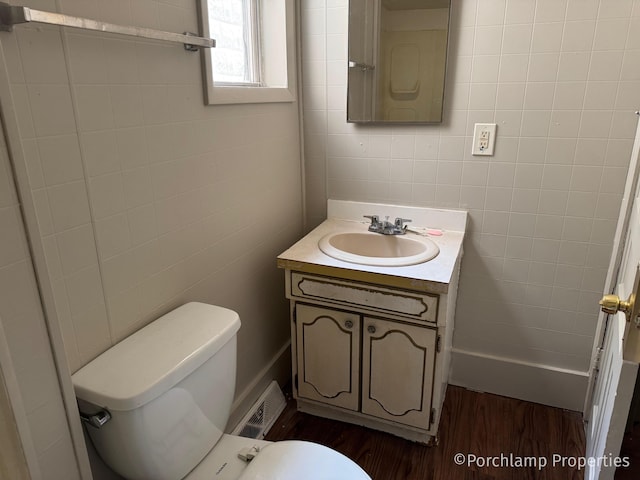 1257 3rd St, Muskegon, MI 49441 - bathroom with tile walls, wood finished floors, vanity, and toilet