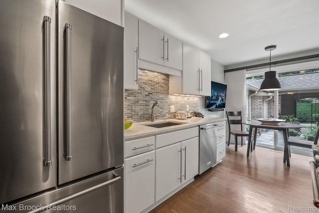 1132 Hillpointe Cir, Bloomfield Hills, MI 48304 - kitchen with appliances with stainless steel finishes, a sink, backsplash, wood finished floors, and hanging light fixtures
