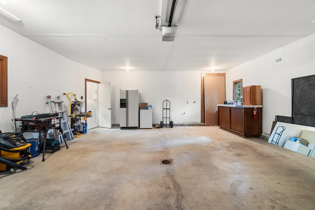 1931 Charlotte Landing Rd, Springport, MI 49284 - garage featuring white fridge with ice dispenser and a garage door opener