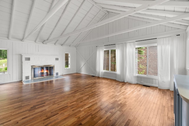 1931 Charlotte Landing Rd, Springport, MI 49284 - unfurnished living room featuring hardwood / wood-style flooring, beam ceiling, a glass covered fireplace, wooden walls, and high vaulted ceiling