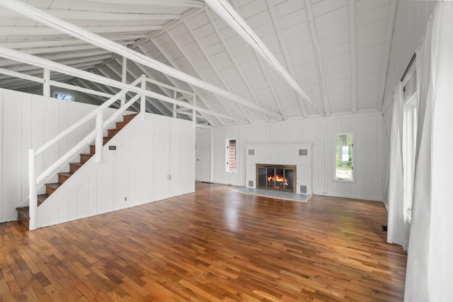 1931 Charlotte Landing Rd, Springport, MI 49284 - unfurnished living room with high vaulted ceiling, wood finished floors, a glass covered fireplace, beam ceiling, and stairway