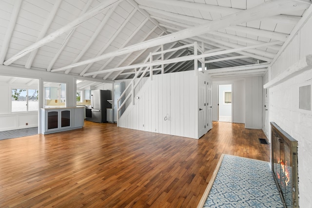 1931 Charlotte Landing Rd, Springport, MI 49284 - unfurnished living room featuring dark wood-type flooring, a fireplace, beamed ceiling, and high vaulted ceiling