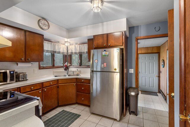 13405 Ellis Rd, Conklin, MI 49403 - kitchen with appliances with stainless steel finishes, a sink, light countertops, light tile patterned floors, and brown cabinetry