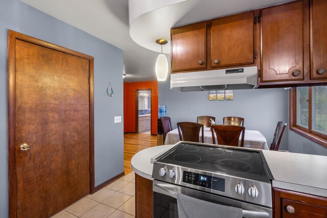 13405 Ellis Rd, Conklin, MI 49403 - kitchen featuring stainless steel electric stove, under cabinet range hood, light countertops, brown cabinetry, and light tile patterned floors